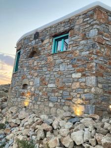 佐努萨岛Dimitrakis Guesthouse的石头建筑,上面有窗户,堆着一堆岩石
