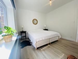 德哈恩Lovely, renovated appartment, near the beach.的白色的卧室配有一张床和墙上的时钟