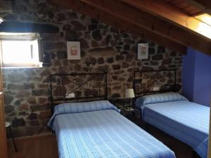 HeradaCasa Rural La Barcenilla的石墙客房的两张床