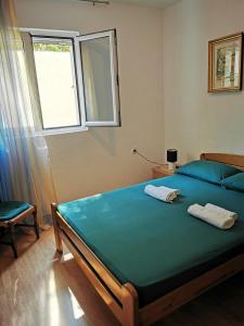 斯韦蒂·斯特凡Apartments Vila Andja的一间卧室配有一张带蓝色床单的床和一扇窗户。