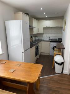 利物浦Quiet 5 bed apartment in Liverpool的厨房配有白色冰箱和木桌