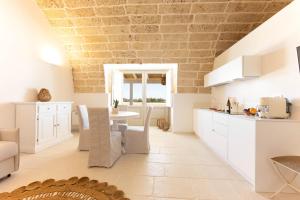 加利波利Masseria Macchiaforte的厨房以及带白色橱柜和桌子的用餐室。