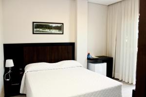 廷博蓝山酒店的卧室配有一张白色的大床和一张桌子