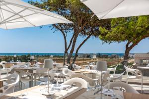 萨尔维Perla Saracena Hotel & Restaurant的一间设有白色桌椅和遮阳伞的餐厅