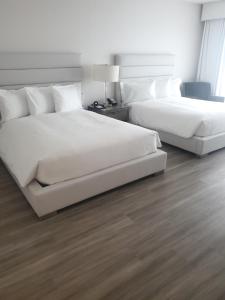 森尼维耳市格兰酒店的配有白色床单的酒店客房内的两张床