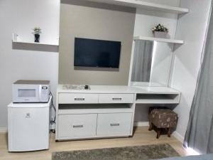 佩尼亚Cantinho da Vila Hospedagem的客房内的白色书桌配有微波炉和电视。