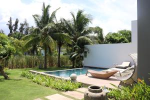 何科克Villa 135, Sanctuary Ho Tram的后院设有游泳池、椅子和棕榈树
