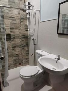 曼巴豪RedDoorz at Gracia's Calzada Inn Camiguin的浴室配有卫生间、盥洗盆和淋浴。