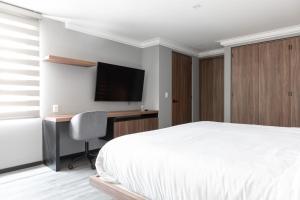 墨西哥城Capitalia - Apartments - Polanco - Julio Verne的一间卧室配有一张床、一张书桌和一台电视