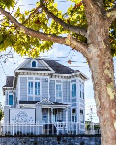 圣克鲁兹Rio Vista Inn & Suites Santa Cruz的白色的栅栏和一棵树的蓝色房子
