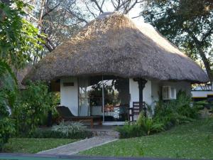 卡蒂马穆利洛Caprivi River Lodge的茅草屋顶和长凳的小小屋