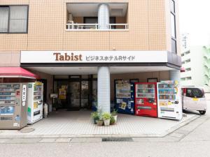 金泽Tabist Business Hotel R Side Kanazawa的大楼前的商店,有自动售货机