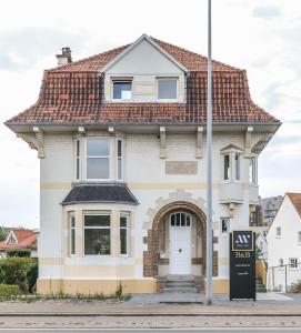 米德尔克尔克Bed & Breakfast Maison Noire Westende-bad incl parking & ontbijt的白色房子,有红色屋顶