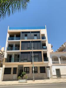 莫切Apartamento NEPTUNO con piscina a 50 mt de la playa的棕榈树街道上的公寓楼