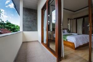 乌布Central Ubud Modern Apartments + Private Kitchen的一间卧室设有一张床和一个玻璃门