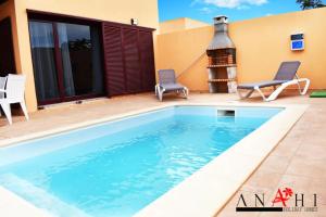 拉奥利瓦Anahi Home Corralejo - Villa Cardon 12的一座带壁炉的房子前面的游泳池
