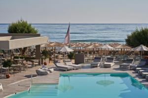 埃亚玛琳娜奈奇多Atlantica Amalthia Beach Hotel - Adults Only的一个带椅子和遮阳伞的游泳池以及大海