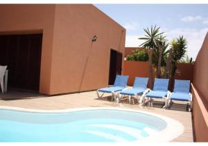 拉奥利瓦Anahi Homes Corralejo - Villa Drago 12的一座带蓝色椅子的游泳池和一座建筑