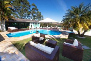 若阿诺波利斯Casa de campo c lazer completo em Joanopolis - SP的后院设有2把椅子和1把遮阳伞的游泳池