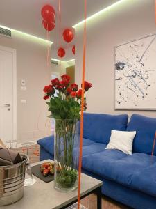 地拉那Light Hotel的客厅配有蓝色的沙发和红玫瑰花瓶
