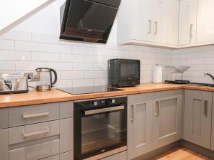 托基Flat 1 Byfield的厨房配有白色橱柜和黑色用具