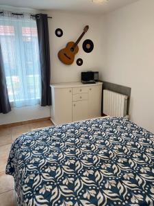 Maison calme et confortable的卧室配有一张床,墙上配有吉他
