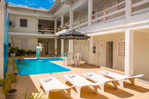 塞古罗港Na Praia Hotel的一个带白色椅子和遮阳伞的游泳池