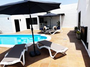 纳萨雷特Nazaret Villa with heated pool的一个带两把椅子和一把遮阳伞的庭院,毗邻一个游泳池