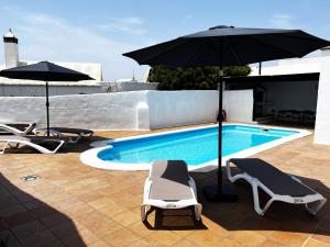 纳萨雷特Nazaret Villa with heated pool的一个带2把躺椅和遮阳伞的游泳池