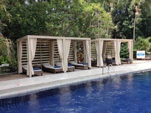 北芭堤雅Let's Hyde Pattaya Resort & Villas - Pool Cabanas的游泳池旁设有椅子和凉亭