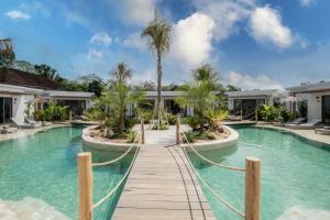 乌鲁瓦图Kalia Bingin - Adult only的一个带木制走道和棕榈树的度假游泳池