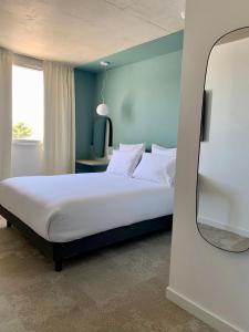 马蒂格Golden Tulip Martigues Provence的卧室配有一张带镜子的白色床