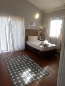 Machadodorp老磨坊酒店的卧室配有床和黑白地毯。