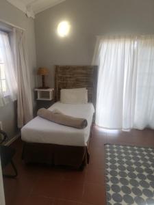Machadodorp老磨坊酒店的一间卧室设有两张床、一个窗户和一个地毯。