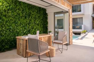 斯卡拉伯塔麦斯Soho Exclusive Suites的庭院设有两把椅子和一张桌子,还有一面绿色的墙壁