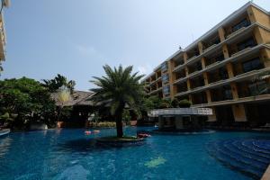 芭堤雅市中心LK Mantra Pura Resort的一座建筑前的游泳池,里面种着棕榈树
