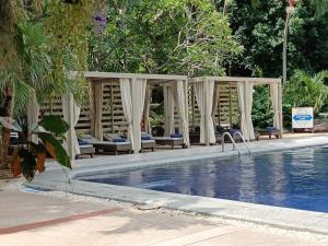 北芭堤雅Let's Hyde Pattaya Resort & Villas - Pool Cabanas的一个带椅子的游泳池和一个凉亭