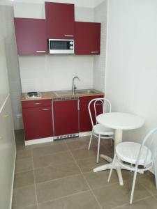 塔兰托Berenice Suite的厨房配有红色橱柜和桌椅