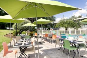 昂格洛里尔西方昂格洛智选假日酒店的一个带桌椅和绿色遮阳伞的庭院