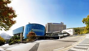 首尔Swiss Grand Hotel Seoul & Grand Suite的一条空的街道,在一座大型玻璃建筑前