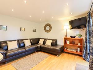 达特福德Willow Cottage的客厅配有真皮沙发和平面电视