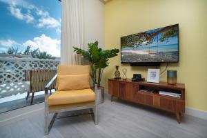 Upper LandLuxury 1 bed apartment near Seven Mile Beach at The Grove - Villa Pina Colada的客厅配有电视和椅子