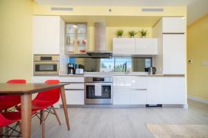 Upper LandLuxury 1 bed apartment near Seven Mile Beach at The Grove - Villa Pina Colada的厨房配有白色橱柜和红色椅子的桌子