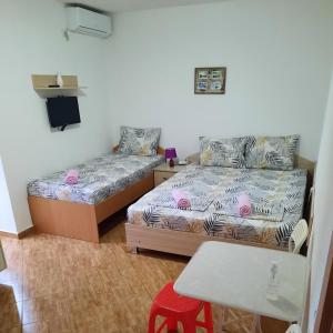 斯塔多伊兰Apartmani Milica Dojran的一间卧室配有两张床、一张桌子和一张凳子