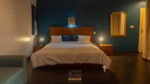 达喀尔O Petit Club Africain Dakar的一间卧室配有一张大床和一把椅子