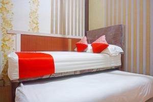 JenepontoOYO 91433 Hotel Sari Jeneponto的一张带红色和白色枕头的床