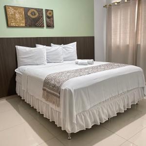 DianópolisHotel Rio Verde的卧室配有一张带白色床单和枕头的大床。