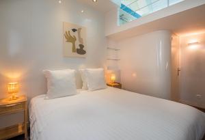 巴黎Makom Pereire的一间卧室配有一张带两盏灯的大型白色床。