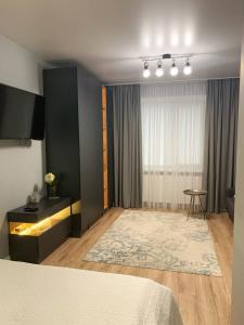 捷尔诺波尔Стильна чудова квартира в місті Тернопіль的一间卧室配有一张床、一张桌子和一个窗户。