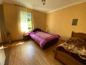 巴统Venera's Guest House的一间卧室设有紫色的床和窗户